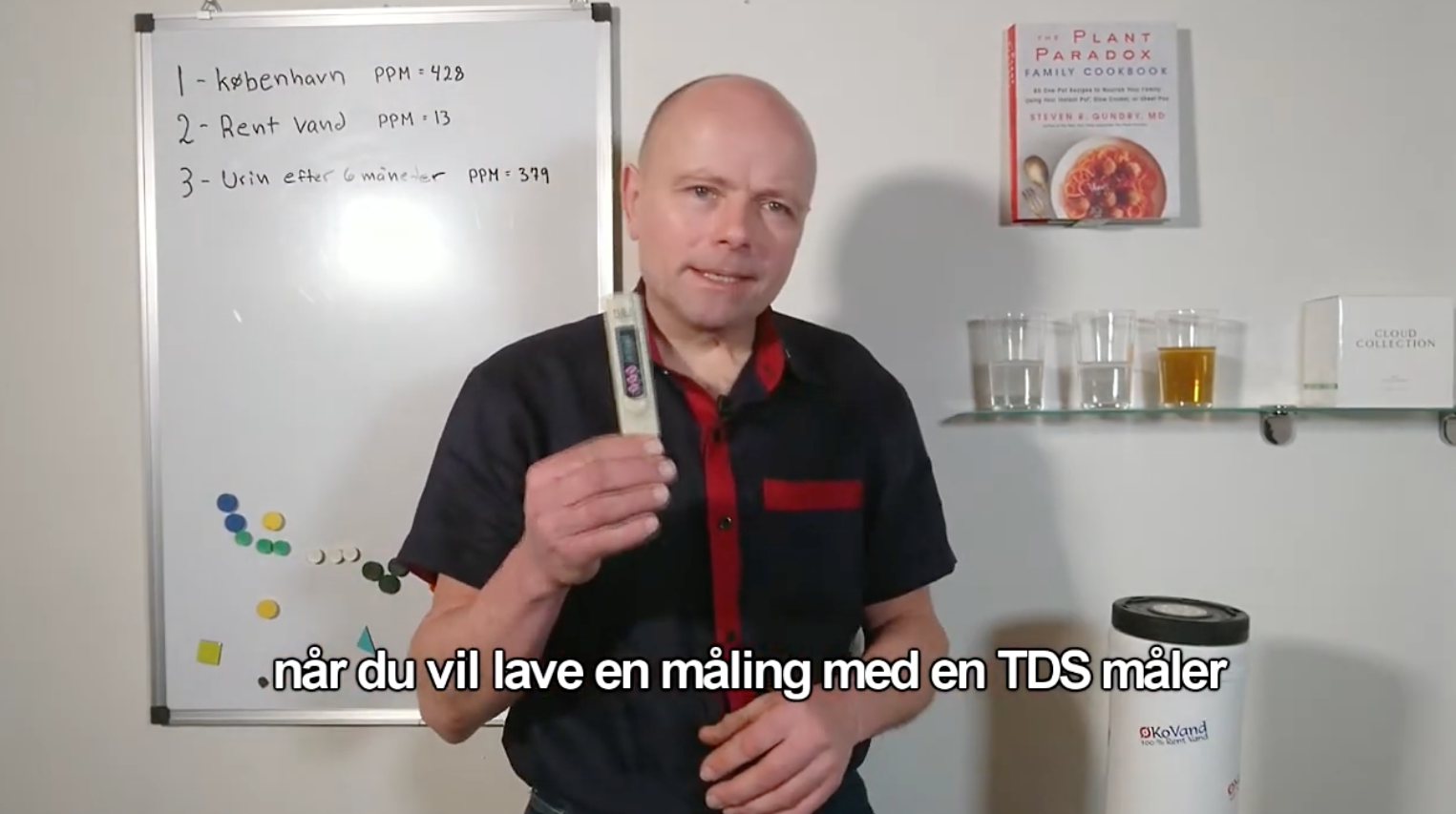Mand holder TDS-måler, white board med PPM-værdier af vand og urin